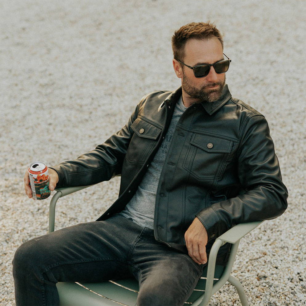 man sitting in chair with drink wearing leather jacket