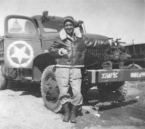 man wearing bomber jacket standing at jeep